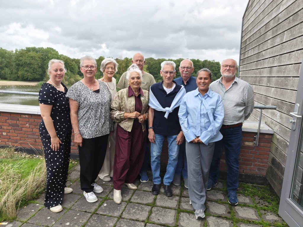 Groepsfoto van leden van de Inwonerraad, buiten op een terras.