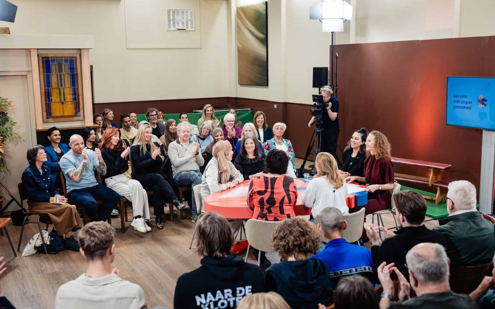 Publiek rond de hartvormige tafel tijdens de talkshow Aan tafel in Alkmaar.